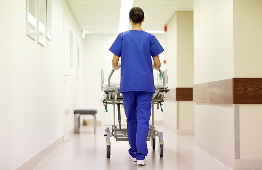 Medical Staff Pushing A Hospital Bed Down The Hallway